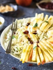 Apples, cheese, cabbage, and raisins, in a bowl with a fork