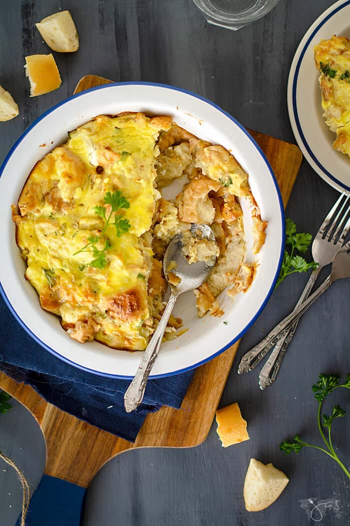 A dish of stale bread, feta cheese, and onions with a spoon resting in it.