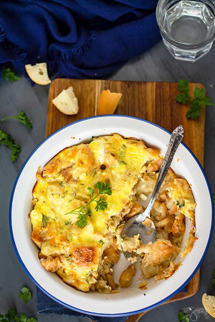 White baking dish with half-eaten bread pudding on a wooden cutting board