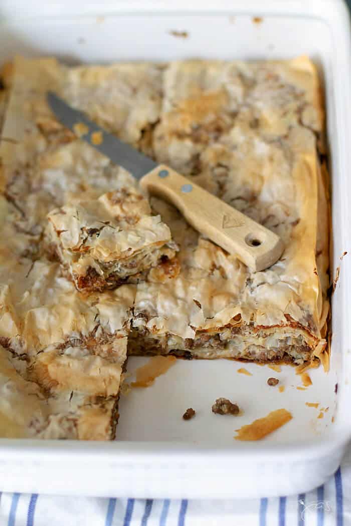 Savory meat filling between layers of crispy fillo pastry sheet