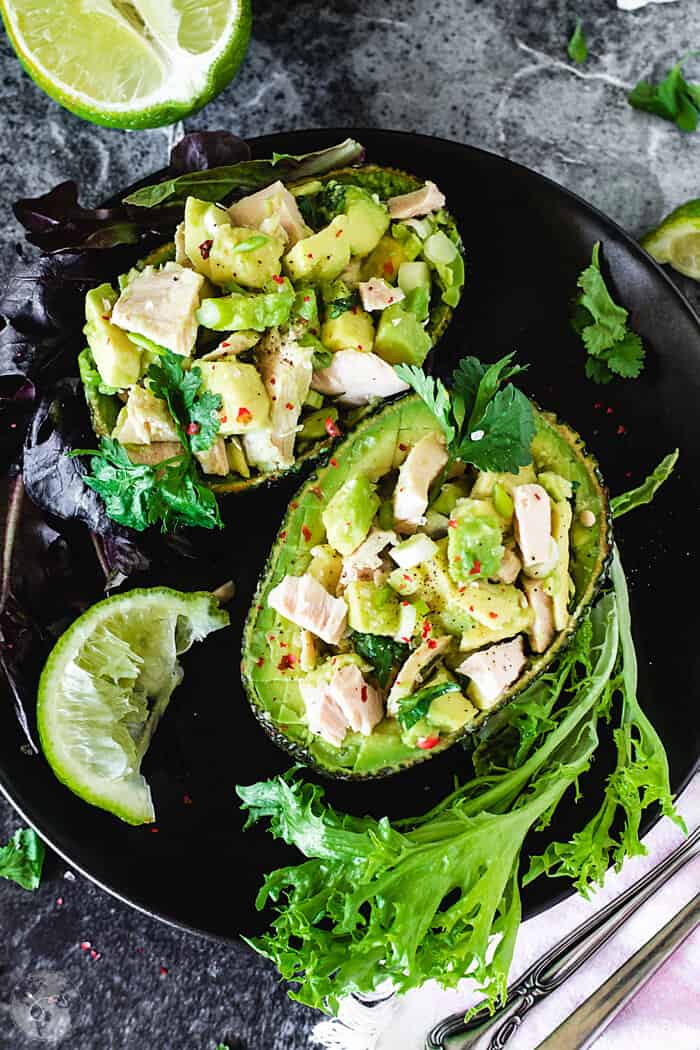 Tuna and avocado salad in avocado skin halves as a vessel with lime wedges.