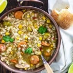 Gumbo soup in a copper bowl with a spoon and bread pieces.