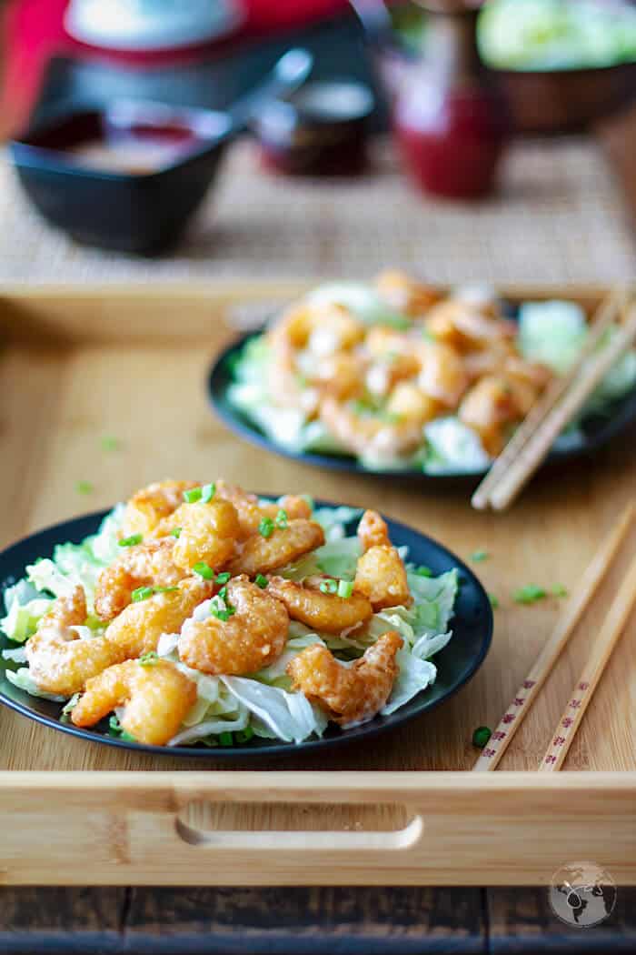 A frontal shot of two shrimp bang bang servings on a wooden tray.