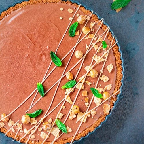 Overhead shot of the German mousse with chocolate and hazelnuts on a dark blue background and garnish.