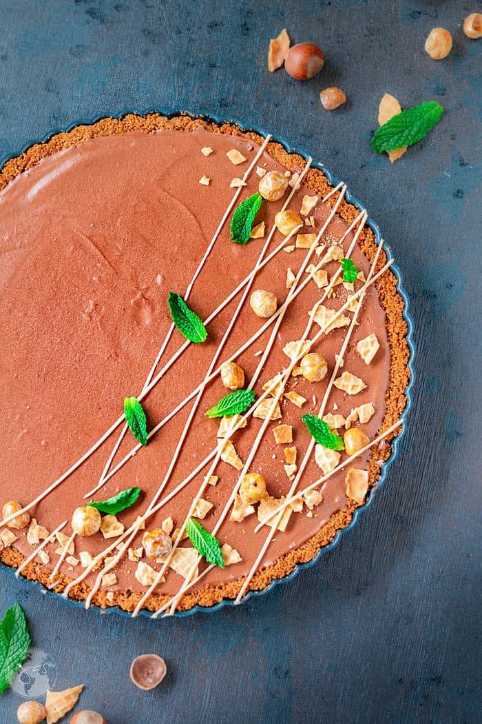 Overhead shot of the German mousse with chocolate and hazelnuts on a dark blue background and garnish.