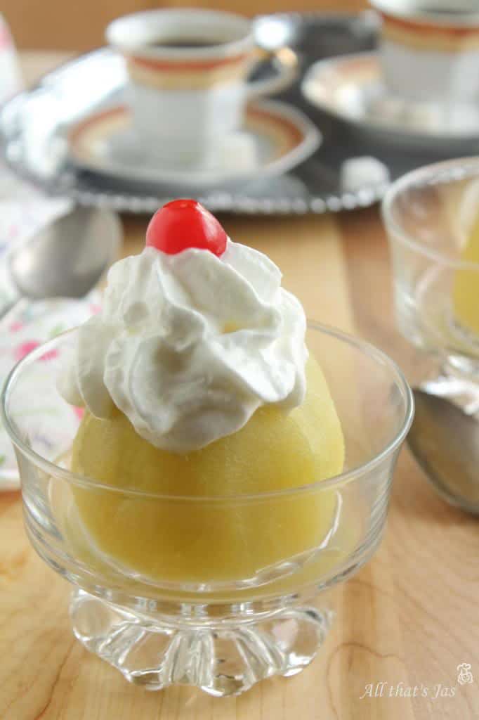 Poached apple in a glass with whipped cream.