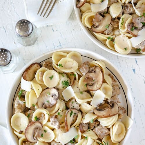 Creamy pasta with homemade sausage served in two bowls on white background.