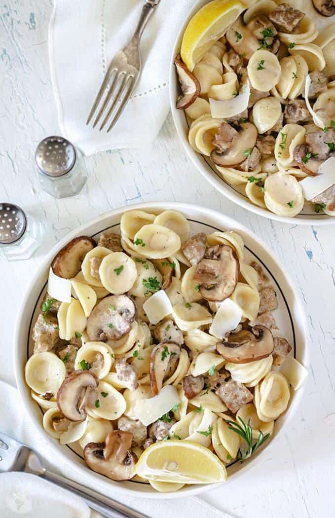 Creamy pasta with homemade sausage served in two bowls on white background.