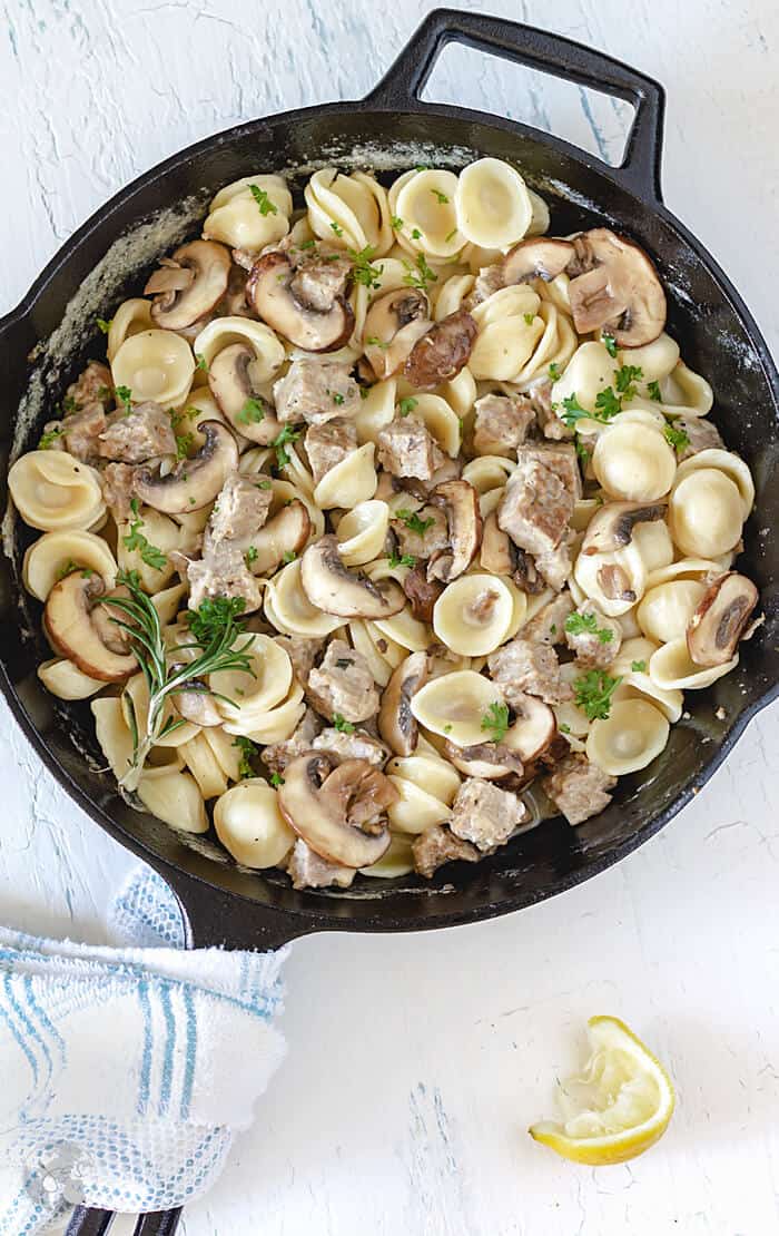 A cast-iron skillet with creamy orecchiette, mushrooms, and sausage.