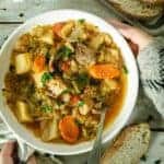 Placing a bowl of cabbage soup on a wooden table.