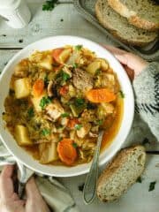 Placing a bowl of cabbage soup on a wooden table.