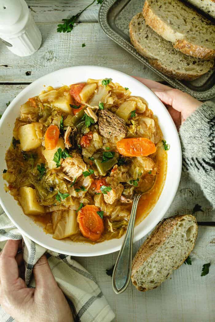 Placing a bowl of cabbage soup on a wooden table.