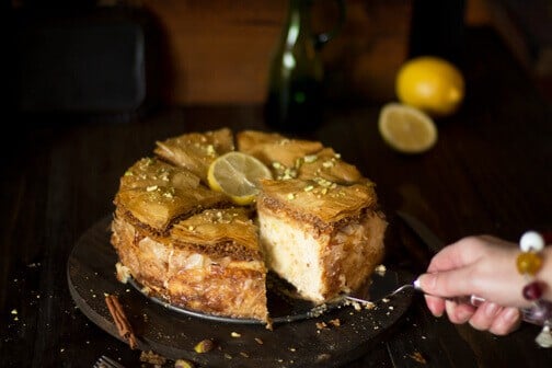 A person serving a piece of baklava cheesecake.