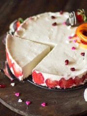 A cheesecake with fruit on a wooden serving platter