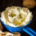 A blue pot with a handle filled with mashed potatoes