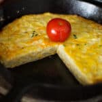 Frittata piece in a pan and tomato.