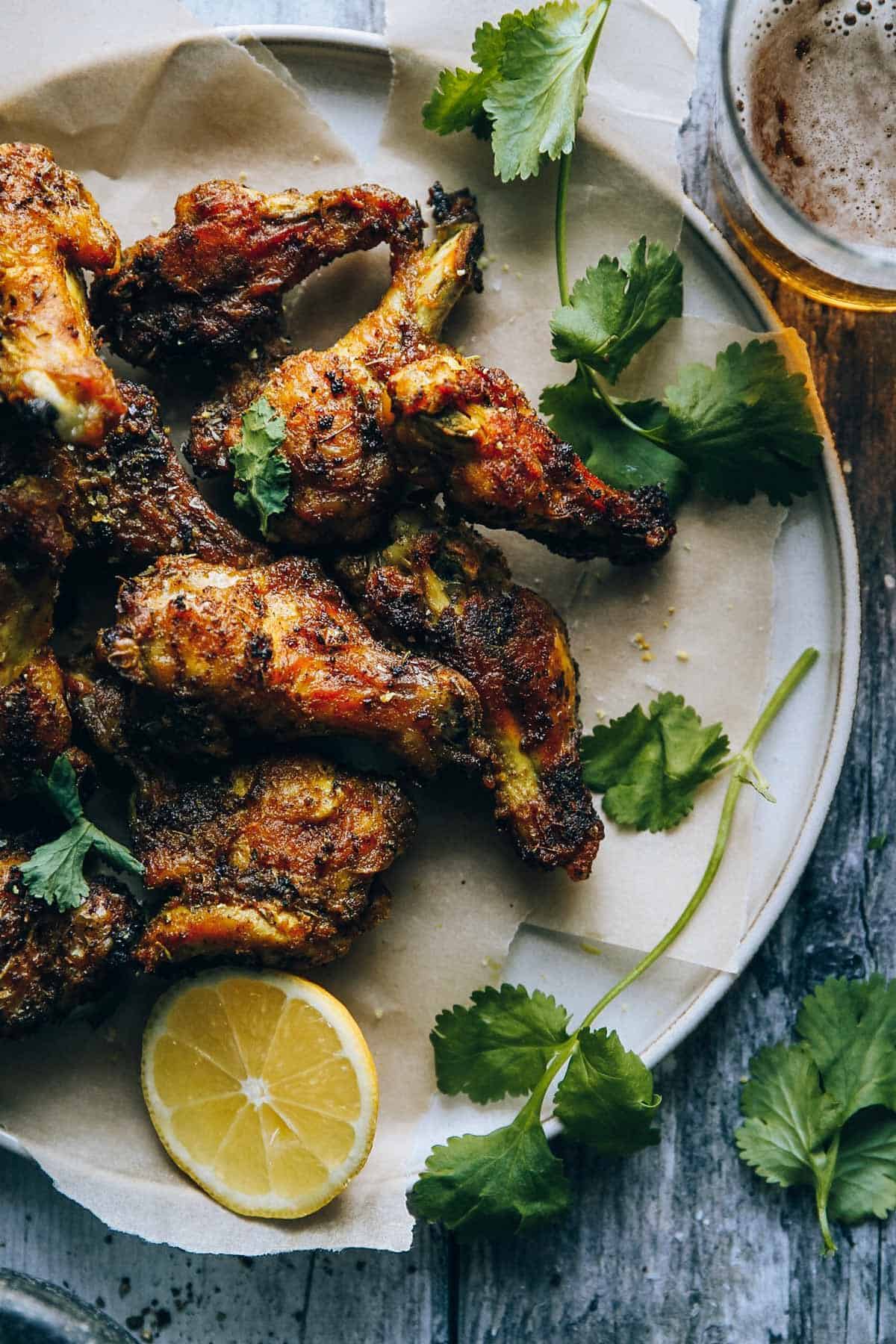 Close up of the crispy wings on a plate with cilantro and lemon.