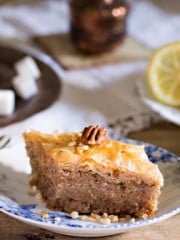 A piece of baklava on a small plate and coffee cup