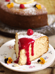 A piece of cake on a plate with raspberry and sauce