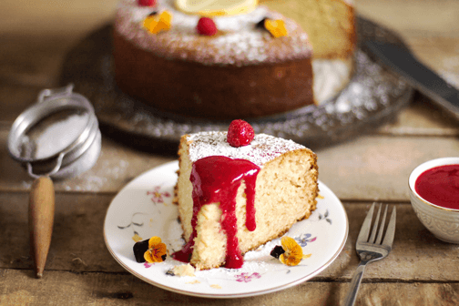 A piece of cake on a plate with raspberry and sauce