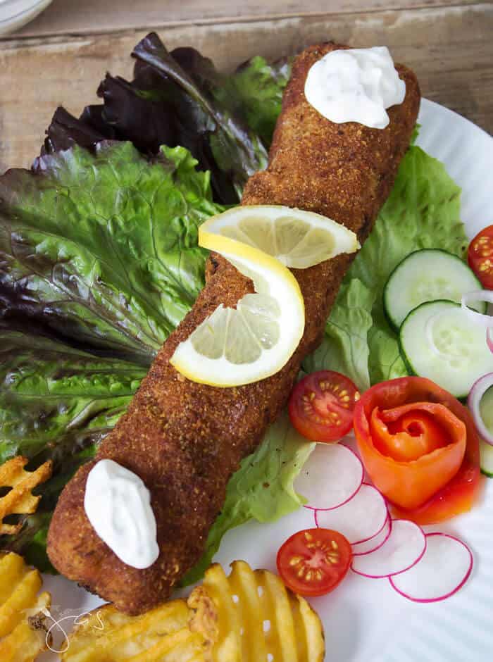 A piece of breaded rolled up cutlet with salad on a plate