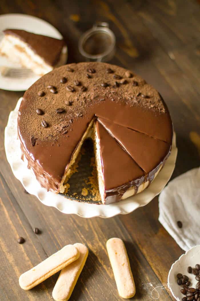 An overhead photo of a cake on a stand and lady finger cookies