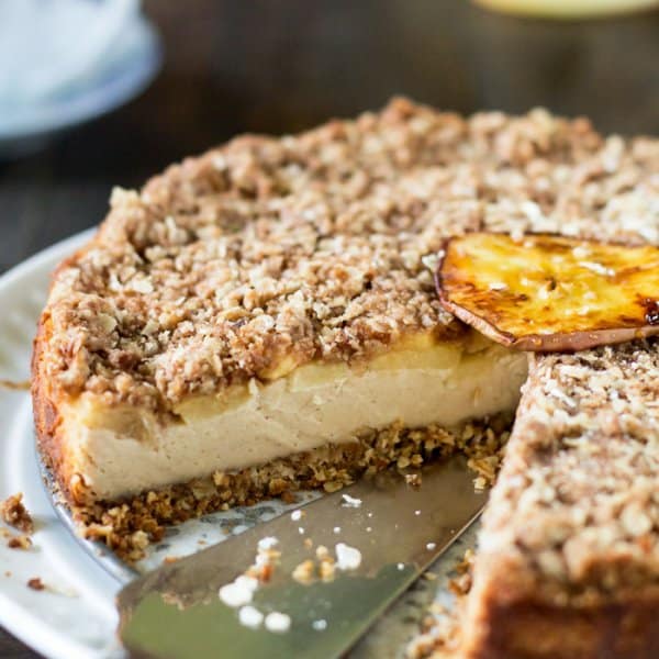 A whole apple oatmeal cheesecake on a plate with one slice removed