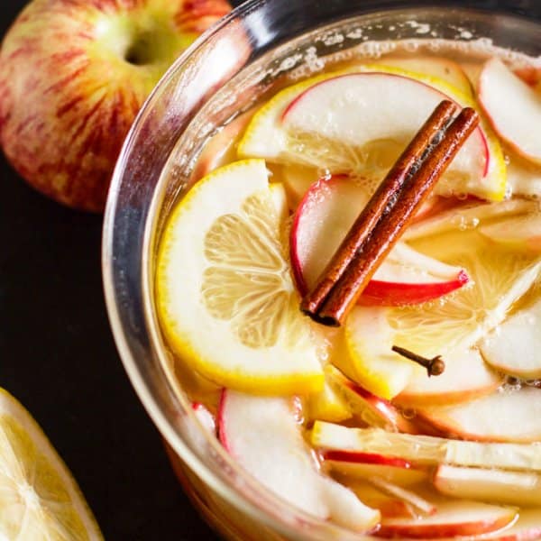 A pan with apples, lemon, and cinnamon sticks.