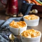 Individual pot pies with vegetables on a table with spoons.