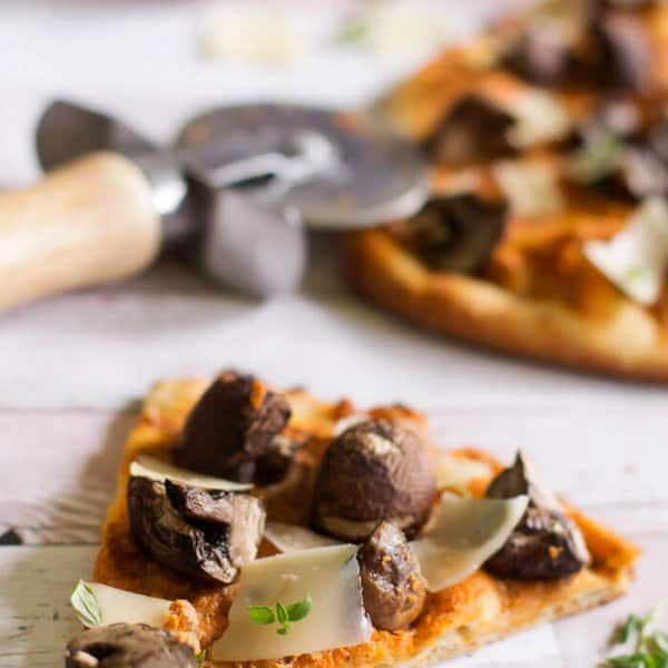 A slice of naan flatbread pizza with goat cheese and mushrooms