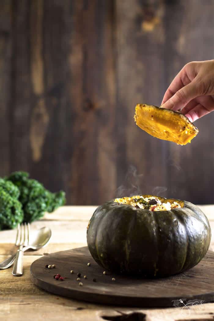 A person removing the top of the roasted stuffed buttercup squash