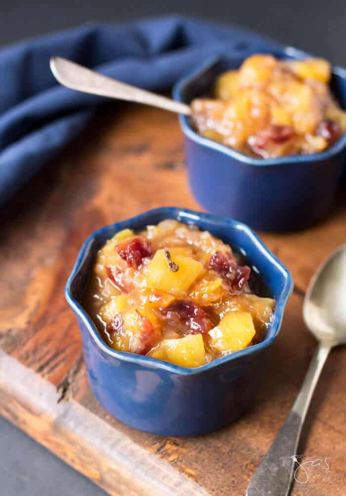 Two blue ramekins with mango chutney and spoons