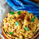 Overhead shot of West African rice dish in a bowl with a blue towel on the side.