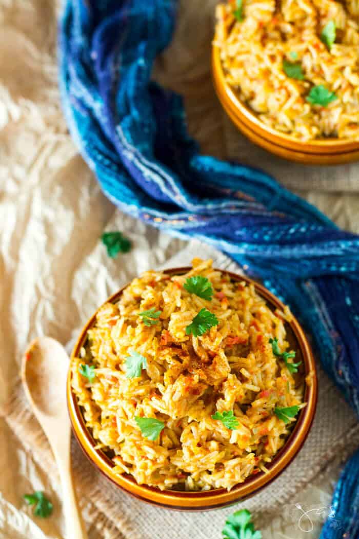 An overhead shot of African rice dish in two bowls sprinkled with cilantro.