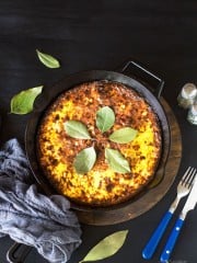 Bobotie in a cast-iron skillet on a black background.