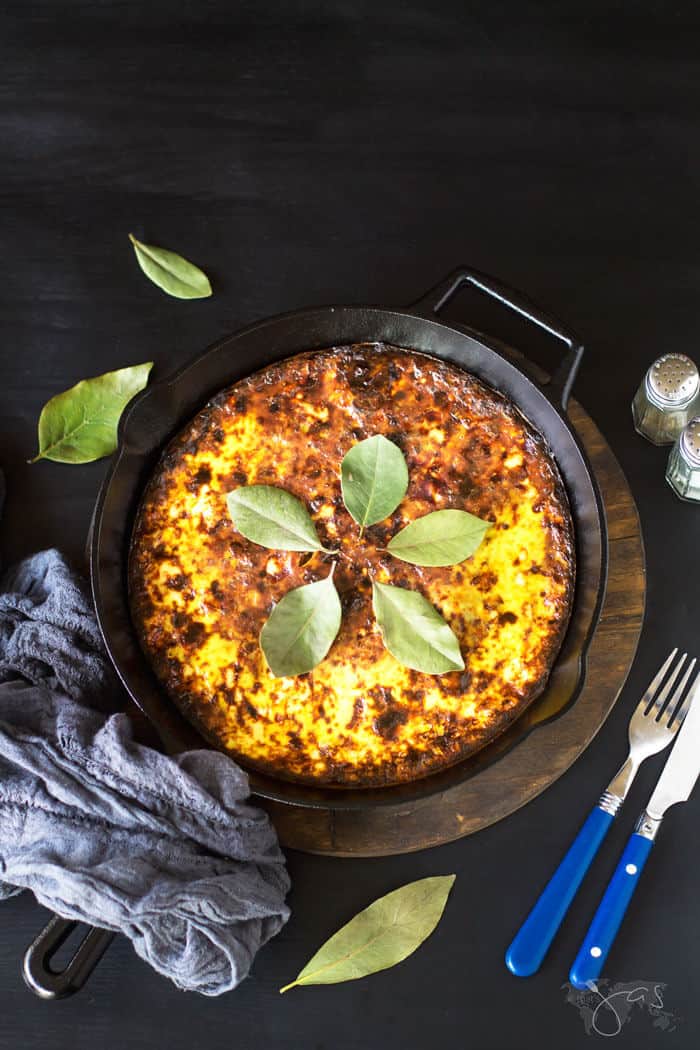 Bobotie in a cast-iron skillet on a black background.