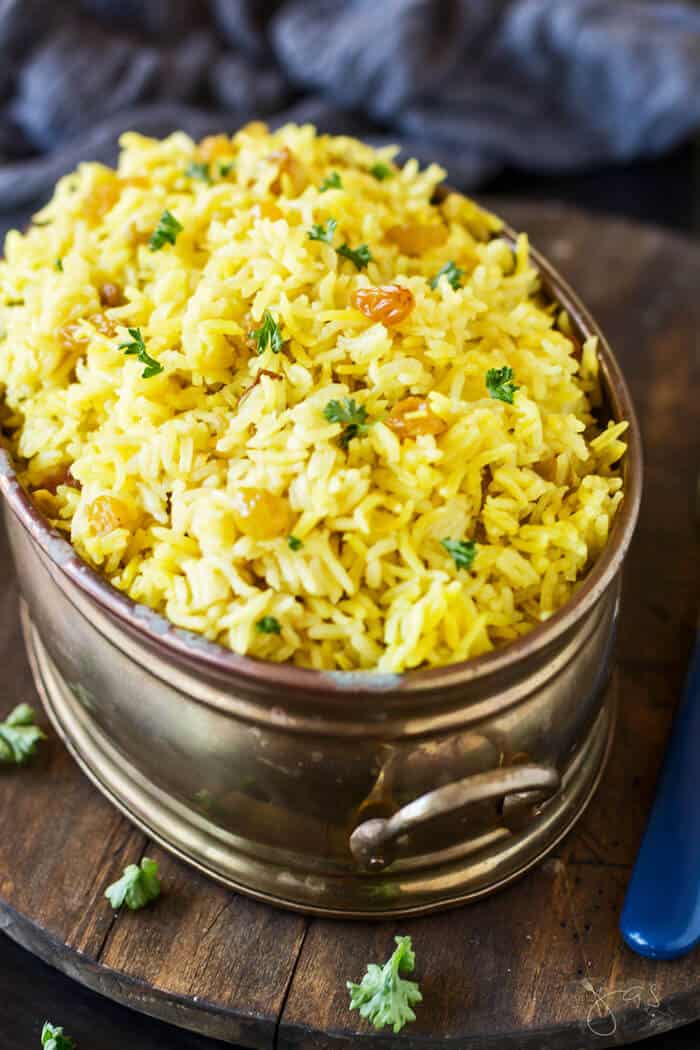 South African sultana yellow rice in an oval copper dish on a wooden trivet. 