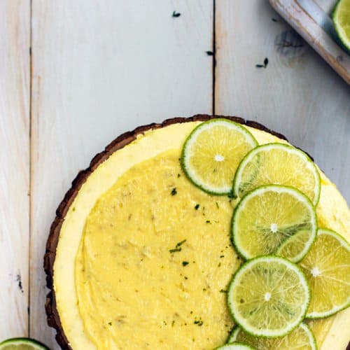 Cheesecake with sliced lime rounds on a white background, from above