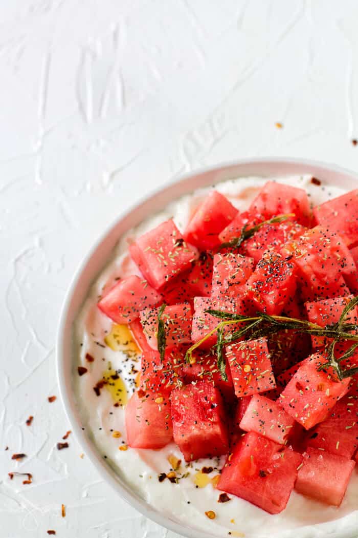 A shot of half the plate with savory watermelon salad on the white textured background.