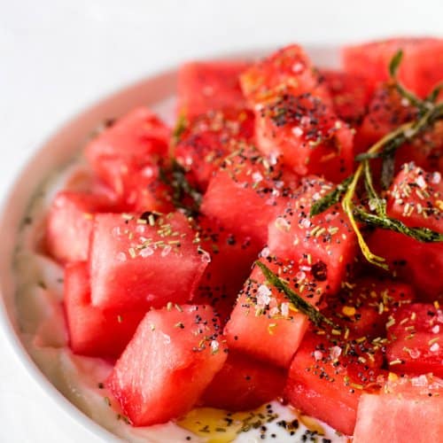 Israeli watermelon salad sprinkled with rosemary, oil, and poppy seeds.