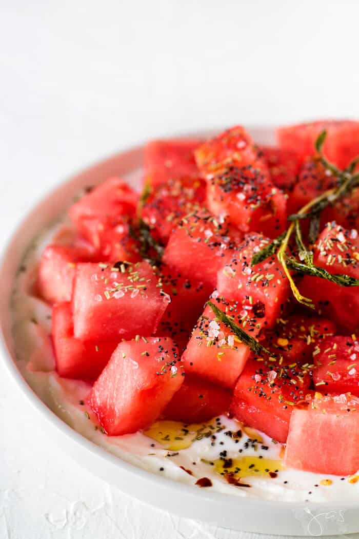 Israeli watermelon salad sprinkled with rosemary, oil, and poppy seeds.