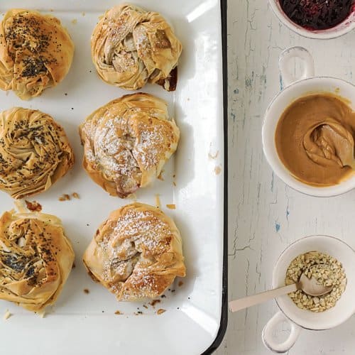 An overhead shot of pan with PB&J donuts with small bowls filled with peanut butter, jelly, and sesame seeds