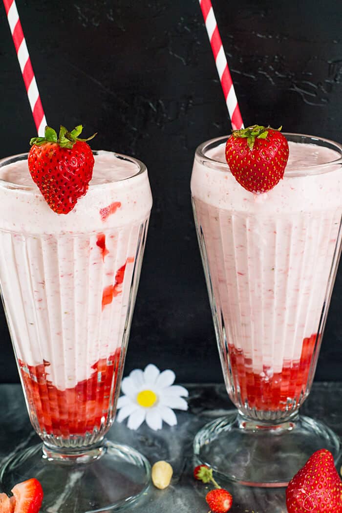 Healthy yogurt smoothie in two glasses with straws and fresh strawberries. 