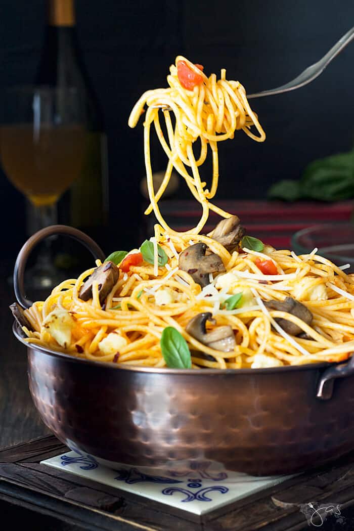 A fork with spaghetti over a bowl with food.