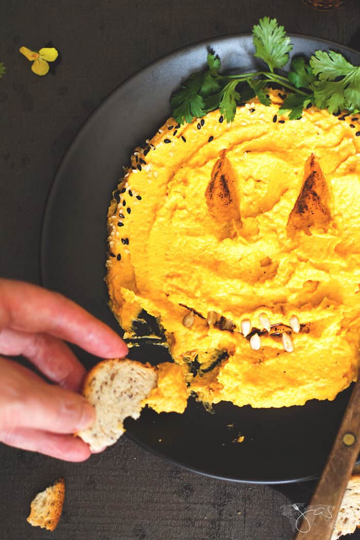 Dipping bread into Lebanese hummus with pumpkin.