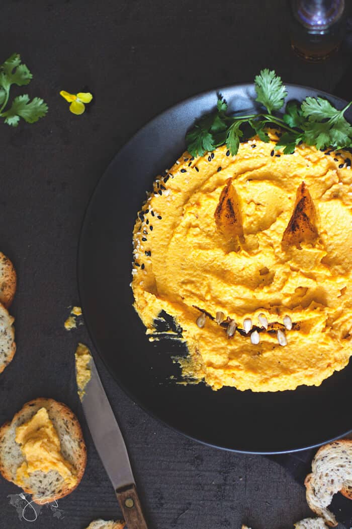 An overhead shot of "scary face" pumpkin dip on a black background