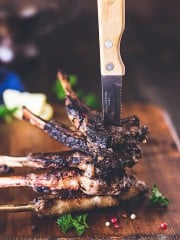 A stack of lambchops held by a knife pierced through them.