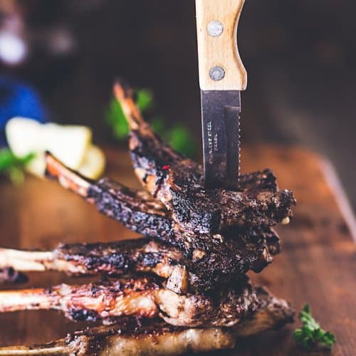 A stack of lambchops held by a knife pierced through them.