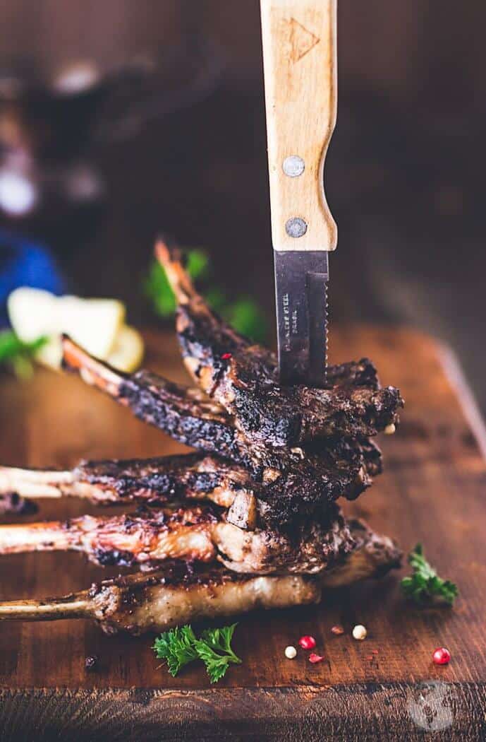A stack of lambchops held by a knife pierced through them.