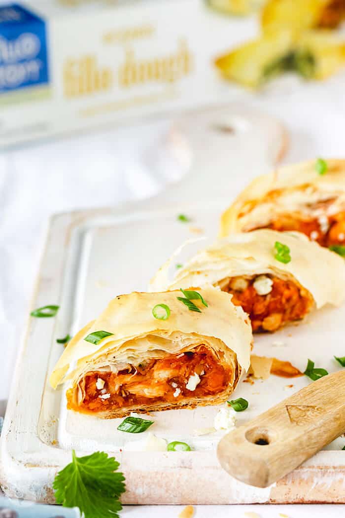 A shot of three stromboli rolls on a white wooden board with fillo package in the background,